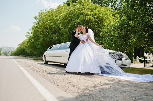 Married couple in front of a limousine preparing for their honeymoon.