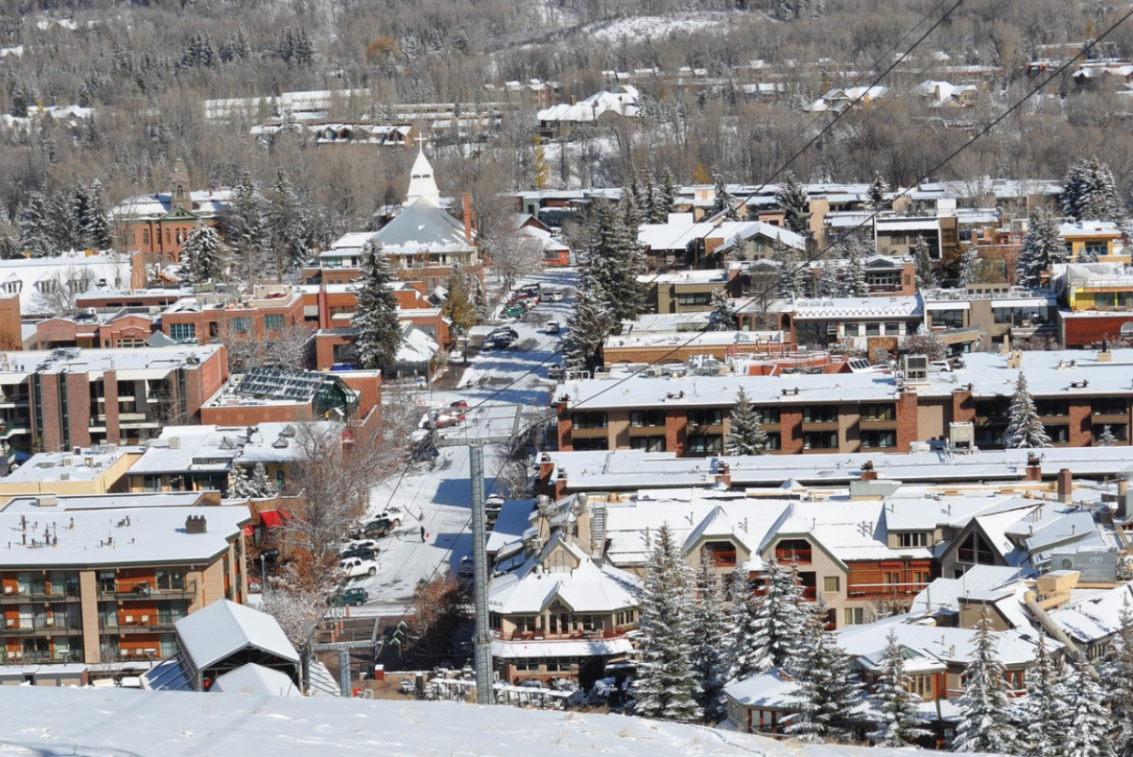 Snow-covered mountain town with buildings and pine trees.